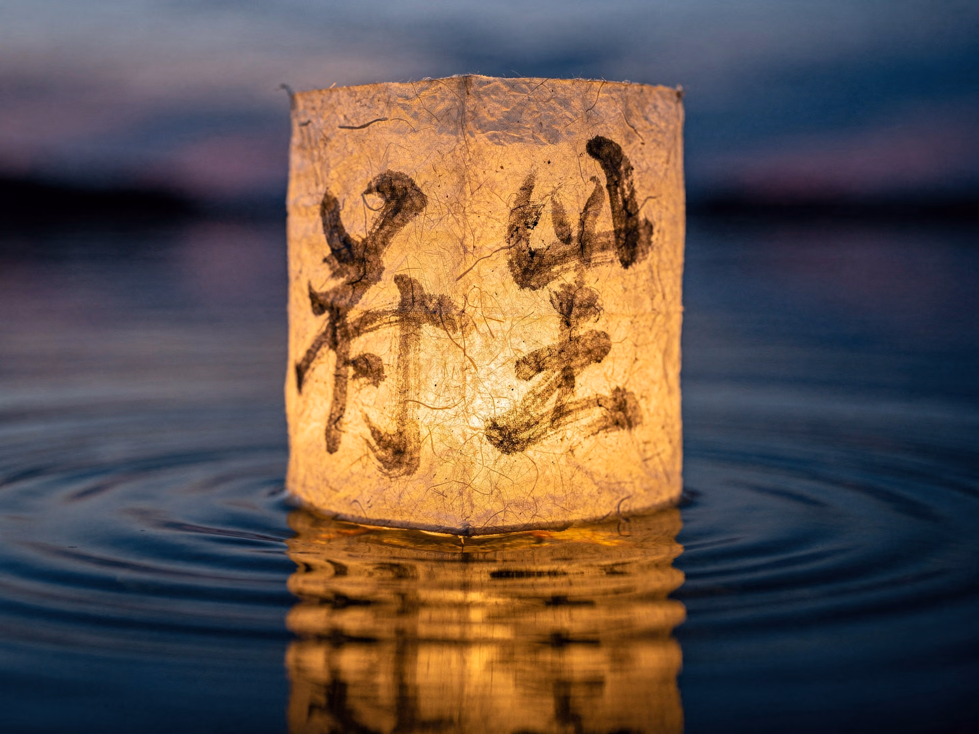 Nahaufnahme einer traditionellen japanischen Papierlaterne mit Kalligraphie auf ruhigem Wasser